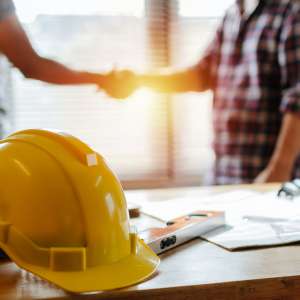 Consutruction contractor shakes hand in an office with yellow safety helmet to start up a business.